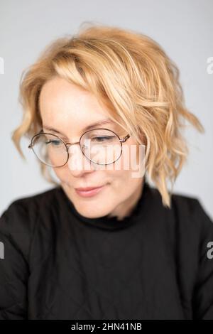 Close up portrait beautiful blonde woman in eyeglasses looking down Stock Photo