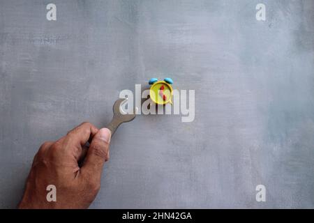 Maintenance and technical support concept. Top view image of alarm clock and hand holding spanner. Stock Photo
