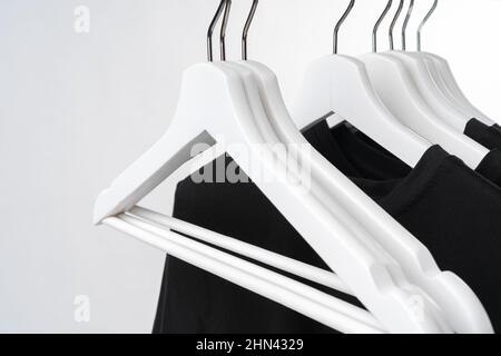 Black T-shirt on hangers on metal rack isolated on white background Stock Photo
