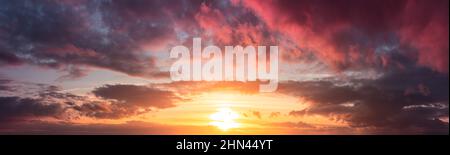 Yellow and warm sunset from gray clouds. Panorama of the dramatic evening sky above the horizon. Stock Photo