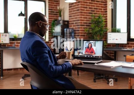 Entrepreneur using online video call to talk to woman on laptop for project planning. Business man meeting with person on remote video conference, having conversation about strategy. Stock Photo