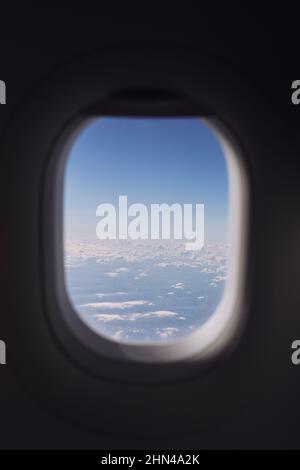 Window of airplane during flight above clouds on beautiful sunny day. Stock Photo