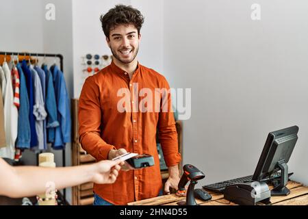 Customer hand paying to shopkeeper man using credit card at clothing store. Stock Photo