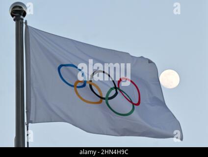 Peking, China. 14th Feb, 2022. Olympia, The moon can be seen behind the flag with the Olympic rings. Credit: Peter Kneffel/dpa/Alamy Live News Stock Photo