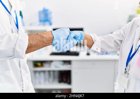 Middle age man and woman partners wearing scientist uniform shake hands at laboratory Stock Photo
