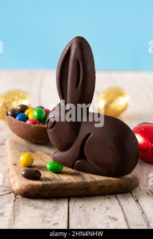 Easter chocolate bunny and colorful eggs on wooden table Stock Photo