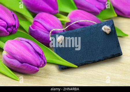 Purple tulips and label on wooden background Stock Photo