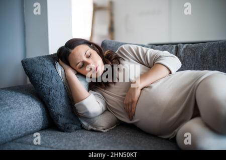 Pregnant woman is relaxing. She is lying on bed at home. Stock Photo