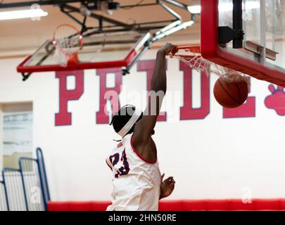 A high school basketball player slam dunking the basketball during a game. Stock Photo