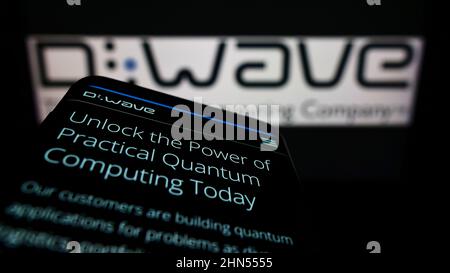 Mobile phone with website of Canadian hardware company D-Wave Systems Inc. on screen in front of logo. Focus on top-left of phone display. Stock Photo