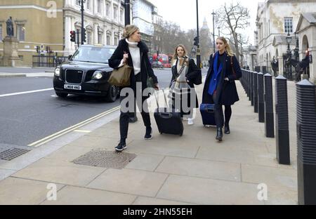London, England, UK. Three women wheeling travel luggage in Whiteshall, Westminster Stock Photo