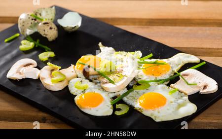 Fried quail eggs with champignons Stock Photo