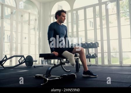 Man with prosthetic leg sitting on a gym bench . He is mentally preparing for his fitness session Stock Photo