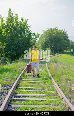 happy traveler with a suitcase walking on the railroad Stock Photo