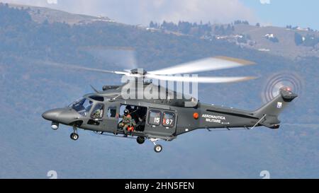Thiene Italy, OCTOBER, 16, 2021 Military helicopter in low altitude flight with the side hatch open and mountains in the background. Agusta Westland A Stock Photo