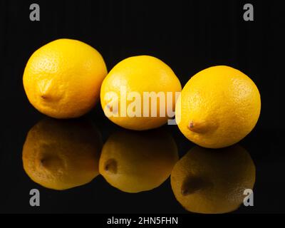 Studio shot of whole lemons isolated on black background. lemon on table with reflection on black background Stock Photo