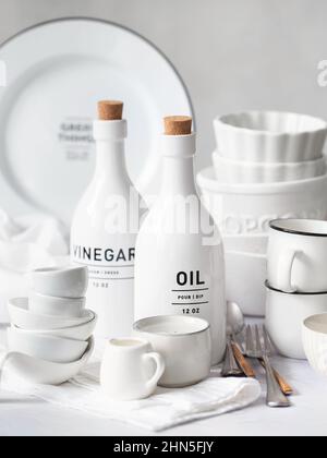 white large and small plates and bowls on a light table. Clean dishes. Set of White clean tableware with black details. White crockery Stock Photo