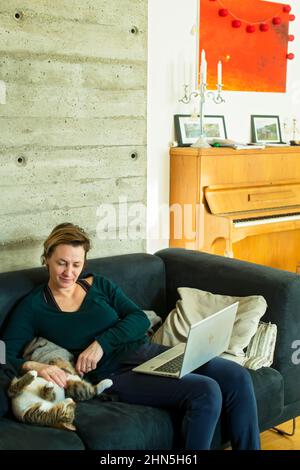 woman sitting on sofa with cat after operation Stock Photo