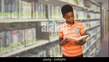 Digital composite image of african american elementary boy reading book while standing in library Stock Photo