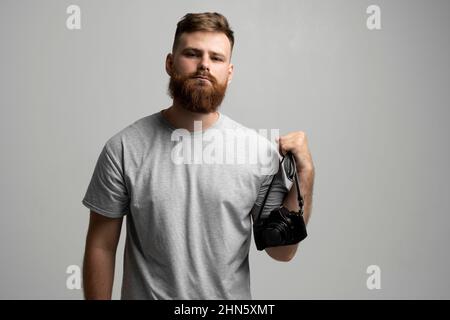Handsome and confident bearded man photographer with a professional camera ready in a hand for take a picture. Stock Photo