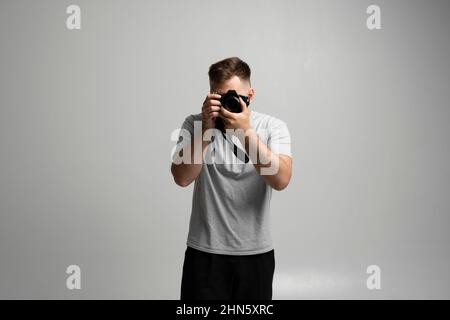 Photography, creative, artist concept. Bearded professional photographer shooting on dslr mirrorless photo camera while working in studio with a model Stock Photo