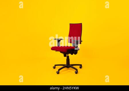 Empty Adjustable Ergonomic Office Chair With Armrests Over Yellow Background Stock Photo