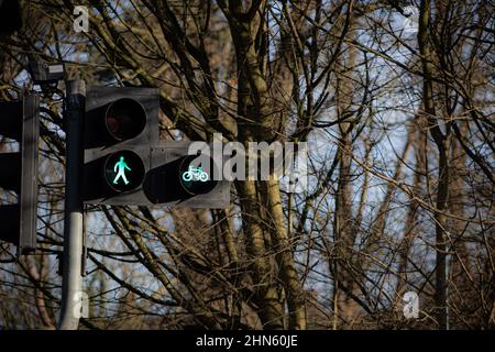 illuminated walking green man and cycle, safe to cross road symbol on a pedestrian crossing at traffic lights. England UK Britain Stock Photo