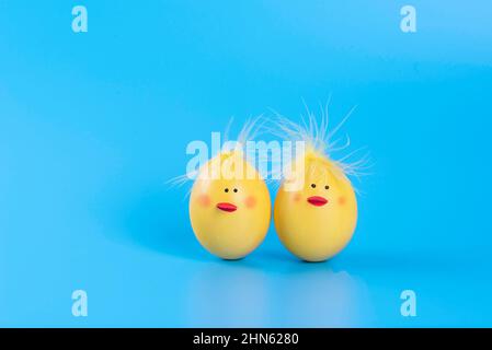 Couple of funny Easter eggs decorated as yellow chicks at the blue background. Stock Photo