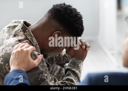 Unrecognizable man placing hand on black soldier shoulder Stock Photo
