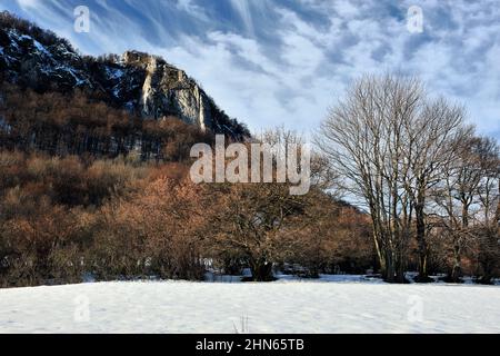 Mountain winter landscape with rock and trees. Beautiful cluster of white clouds. Sunny day, late afternoon. Dramatic blue sky. Vrsatec, Slovakia. Stock Photo