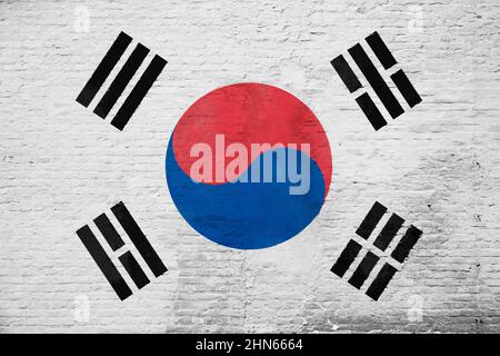 Full frame photo of a weathered flag of South Korea painted on a plastered brick wall. Stock Photo