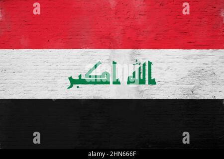 Full frame photo of a weathered flag of Iraq painted on a plastered brick wall. Stock Photo