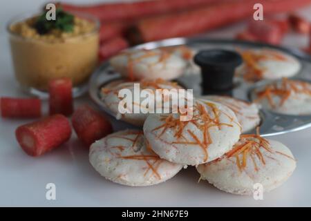 Carrot Idly and coconut chutney. Steamed rice cakes with grated carrots shot with idly mould. Served with spicy coconut condiments. Shot on white back Stock Photo