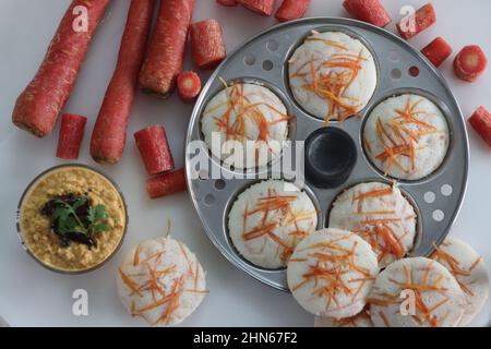 Carrot Idly and coconut chutney. Steamed rice cakes with grated carrots shot with idly mould. Served with spicy coconut condiments. Shot on white back Stock Photo