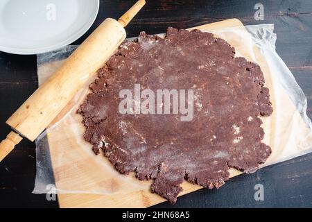 Chocolate Pie Crust Dough Rolled Out into a Circle: Chocolate dough rolled flat with a wooden rolling pin Stock Photo