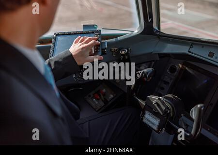 Aircraft pilot sitting in cockpit and using flight display Stock Photo