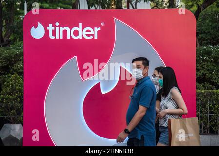 People walk past the 'Tinder' photo booth at the Trimuriti shrine in Bangkok. The 'Pray and swipe right' event organized by online dating app Tinder, with Social distancing Tinder logo markers on the praying ground, a photo booth where people can take profile pictures for their new accounts, and free offering sets, at the Trimuriti shrine on Valentine's day in Bangkok, Thailand. The Trimuriti one of the Hindu gods is known to be the god of love. People come to worship at the Trimurti shrine with offerings of red roses in the hope that they will meet their soulmate. (Photo by Peerapon Boonyakia Stock Photo