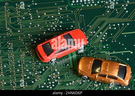 Toy cars on an electronic board with integrated circuits. The shortage of microchips and semiconductors creates a shortage of new cars. Conceptual ima Stock Photo
