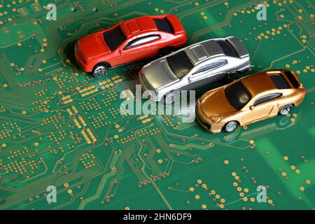 Toy cars on an electronic board with integrated circuits. The shortage of microchips and semiconductors creates a shortage of new cars. Conceptual ima Stock Photo