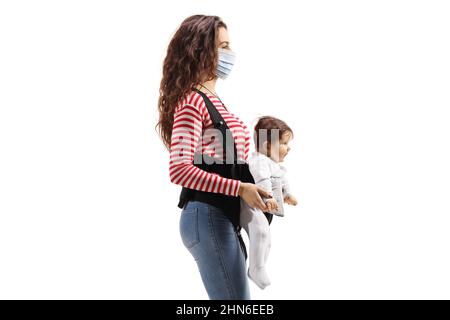 Mother with a baby in a carrier wearing a protective medical mask isolated on white background Stock Photo