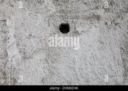 Texture of an old cracked dilapidated worn wall with a hole in the middle Stock Photo