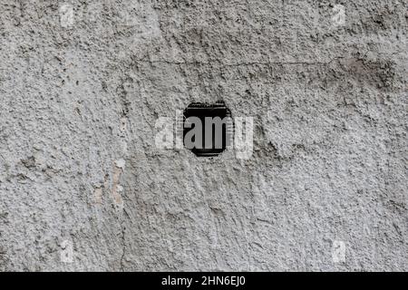 Texture of an old cracked dilapidated worn wall with a hole in the middle Stock Photo