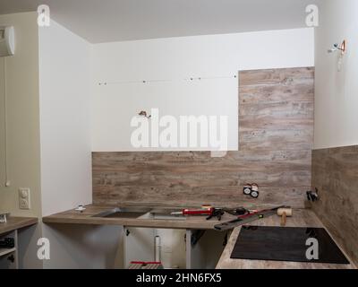 New kitchen - prepared for the assembly of kitchen furniture, cabinets, sink, stove, dishwasher. Tools prepared for professional assembly Stock Photo