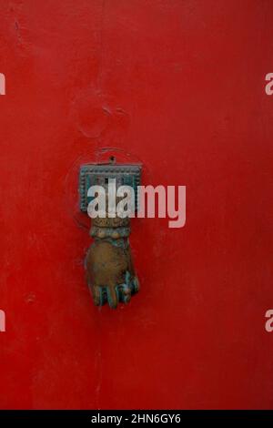old door handle in the shape of the woman's hand on the close-up of the red door. Exterior design. Stock Photo