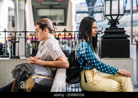 Diverse angry couple sitting in railway station Stock Photo