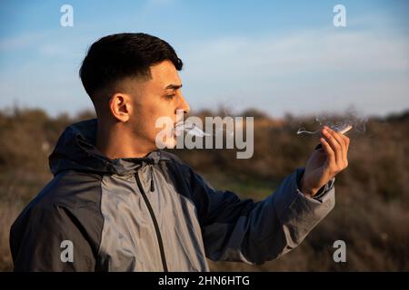 Close-up of young man smoking a marijuana joint outdoors Stock Photo