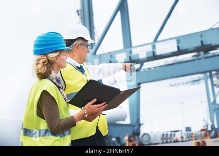 What the boss says goes. Two engineers discussing planning on a site while looking away. Stock Photo