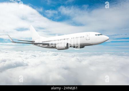 White passenger jet plane in the blue sky. Aircraft flying high through over stratus clouds Stock Photo