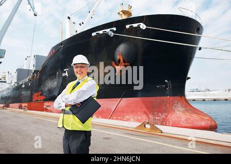 I wouldnt trade my work for anything.. A happy foreman standing with his arms crossed in front of a ship.. Stock Photo