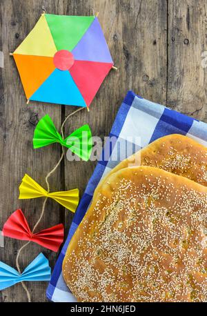 wo lagana breads on checkered tablecloth and colorful kite on wooden table Stock Photo